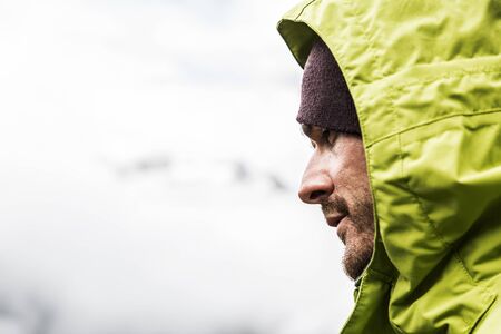 Handsome man profile hooded man on the mountain is looking intentlyの写真素材
