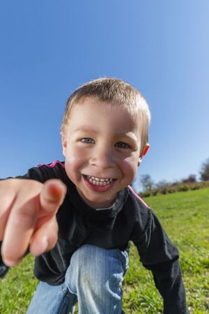 Child smiles at the park is pointing at cameraの写真素材
