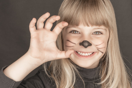 Sweet blond girl with cat costume smile and scratchの写真素材