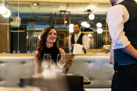Young attractive woman making order at elegant restaurantの写真素材