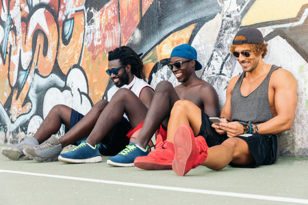 Multiethnic Friends Using Mobile During a Rest After a Street Basketball Game.の写真素材