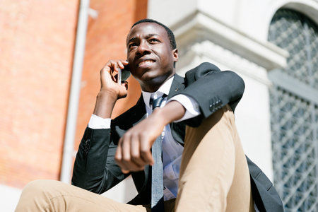 Portrait of Handsome african man smiling when he is using his mobile in the street.の写真素材