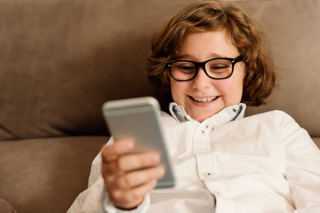 Child boy using his mobile phone at home.