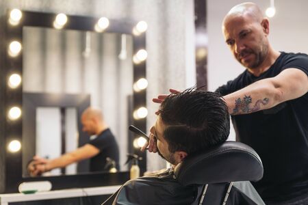 Young Bearded Man Getting Beard Haircut With A Razor By Barber. Barbershop Themeの写真素材