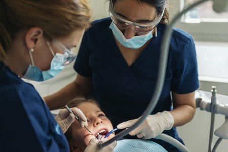 Dentists with a patient during a dental intervention to girl. Dentist  Conceptの写真素材