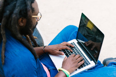 Portrait of african man sitting outside with laptop. Urban work Conceptの写真素材