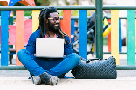 Portrait of african man sitting outside with laptop. Urban work Conceptの写真素材