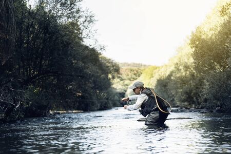 Fly fisherman using flyfishing rod in beautiful river.の写真素材