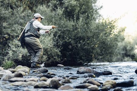 Fly fisherman using flyfishing rod in beautiful river.の写真素材