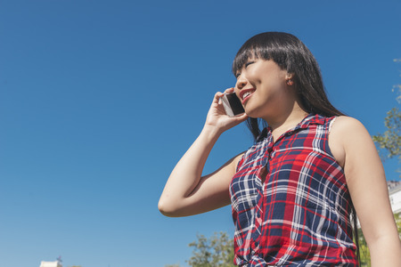 Urban smart casual young asian woman talking on smartphone. Happy female adult speaking on mobile phone.の写真素材