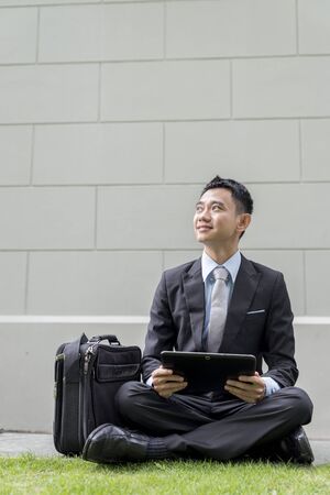 Asian business male using portable computer on park of city. He is lookingの写真素材