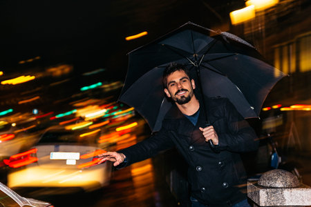 Handsome man walking in Madrid at night in the rain.の写真素材