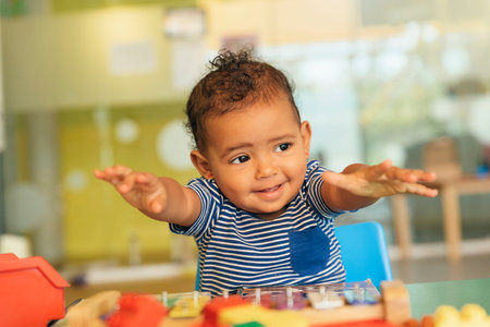 Happy baby playing with toy blocks in the kindergarten.