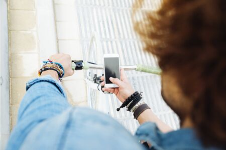 Handsome young man with mobile phone and fixed gear bicycle in the street.の写真素材
