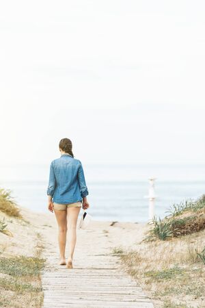 Pretty woman walking away on the idylic beach.の写真素材