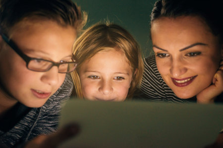 Mother and her children with digital tablet relaxing at home. Family Concept.