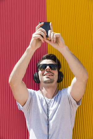 Attractive man with headphones makes selfie with his mobile phoneの写真素材