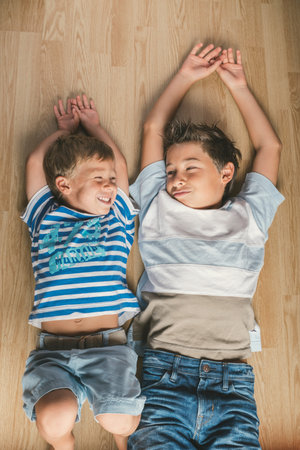 Cute joyful brothers kids lying on a floor at home.の写真素材