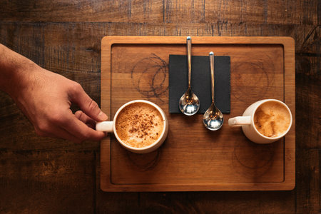 Waiter holding a tray with coffees in the bar.