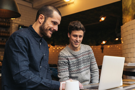 Friends using mobile and laptop in a coffee shop.の写真素材