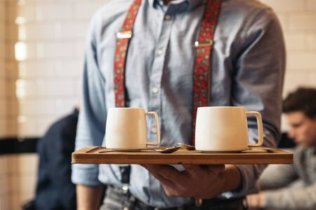 Waiter holding a tray with coffees in the bar.の写真素材