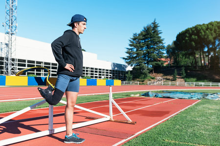 Disabled man athlete stretching with leg prosthesis. Paralympic Sport Concept.