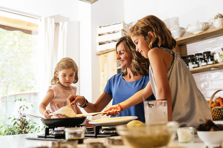 Little sisters cooking with her mother in the kitchen. Infant Chef Concept.の写真素材