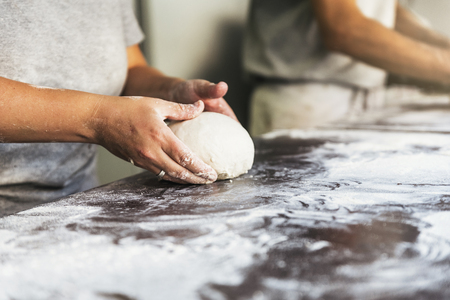 Baker preparing bread. Close up of hands kneading dough. Bakery concept.の写真素材
