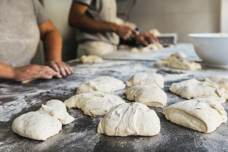 Baker preparing bread. Close up of hands kneading dough. Bakery concept.の写真素材