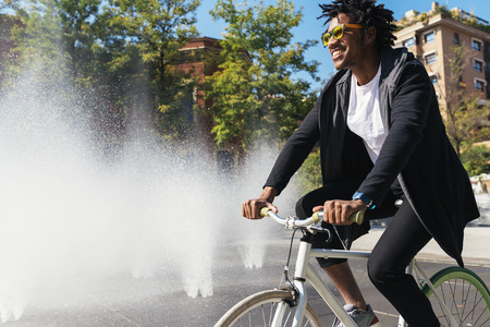 Handsome afro man riding a bike in the street.の写真素材