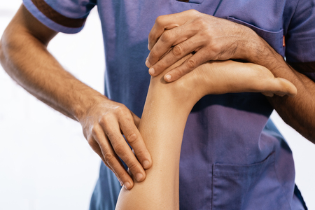 Physiotherapist giving knee therapy to a woman in clinic. Physical treatment conceptの写真素材