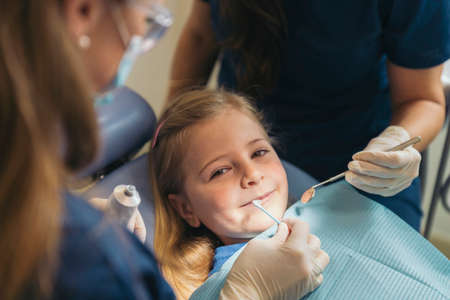 Dentists with a patient during a dental intervention to girl. Dentist Conceptの写真素材