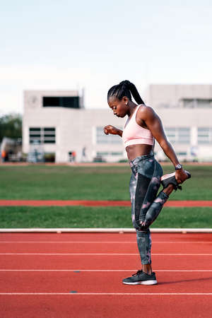 Athlete sprinter stretching her legsの写真素材