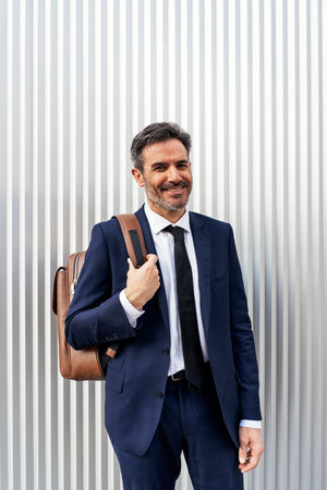 Mature businessman with backpack on streetの写真素材