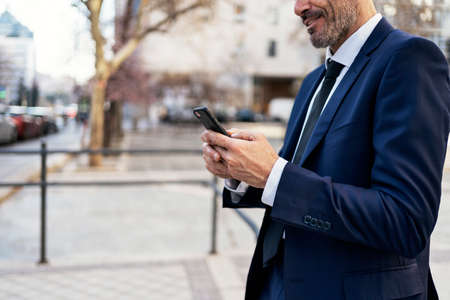 Crop businessman using smartphone on streetの写真素材