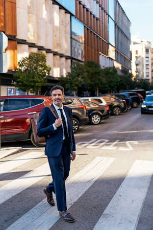 Businessman crossing road in cityの写真素材