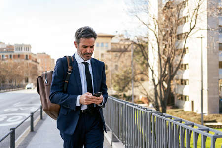 Mature businessman using smartphone on streetの写真素材