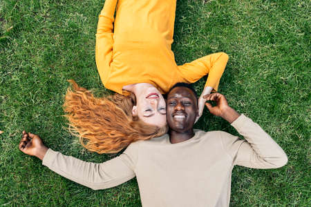 Multiethnic Couple Cuddling in the Grassの写真素材