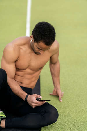 Side view of an Athlete Using Phone in Athletic Trackの写真素材