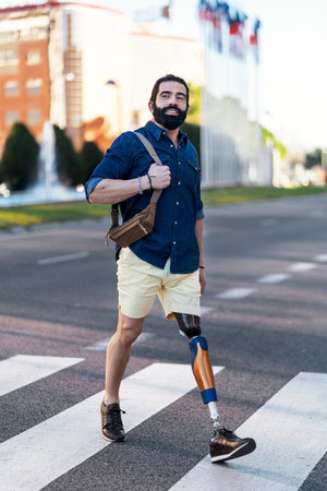 Trendy man with artificial leg crossing road
