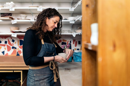 Stock photo of focused woman shaping clay during her pottery class.