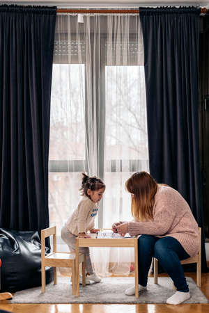 Stock photo of happy woman doing drawings in the living room with her cute daughter.の写真素材