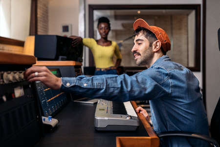 Stock photo of happy black woman in music studio and male producer using electronic piano keyboard.の写真素材