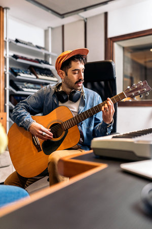 Stock photo of concentrated artist in music studio playing the guitar.