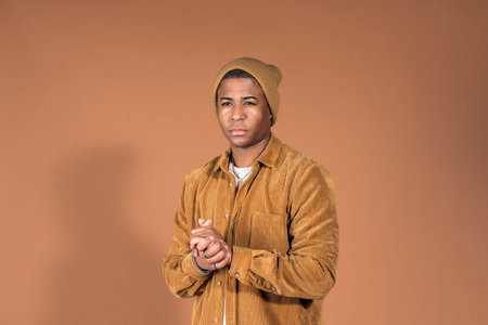Young man wearing casual clothes posing in studio shot against brown background.