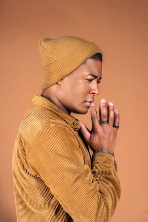 Young man wearing casual clothes posing in studio shot against brown background.