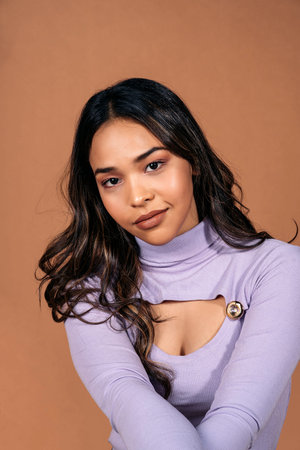 Stock photo of beautiful girl looking at camera against brown background in studio shot.の写真素材