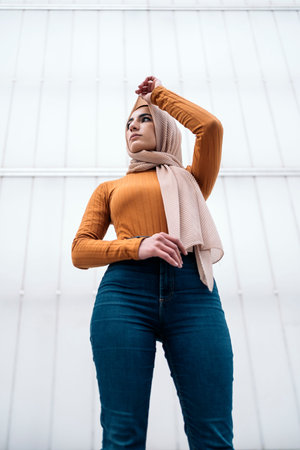 Beautiful young muslim woman wearing hijab standing against white background and looking to the side.の写真素材