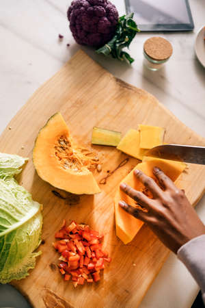 Unrecognized black woman cutting vegetables in the kitchen at home.の写真素材