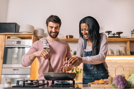 Cute couple smiling and preparing lunch together in the kitchen at home.の写真素材